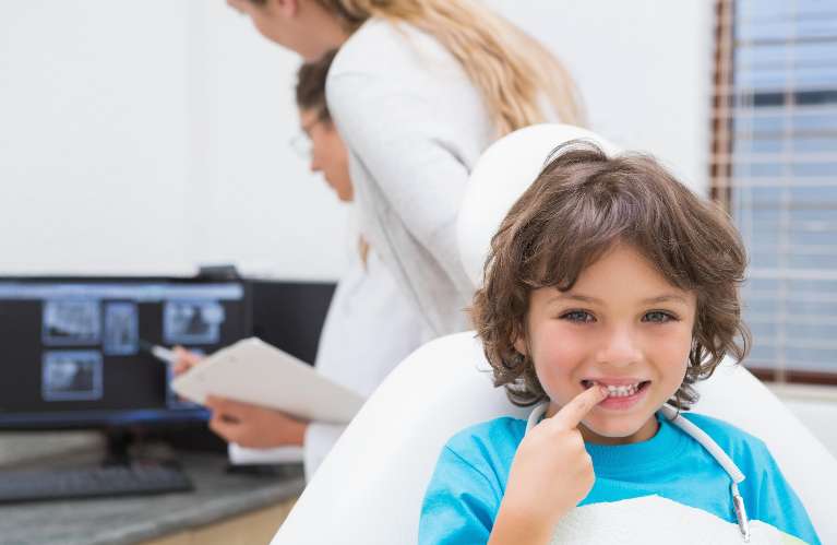 young child pointing to teeth after dental check in troy mi