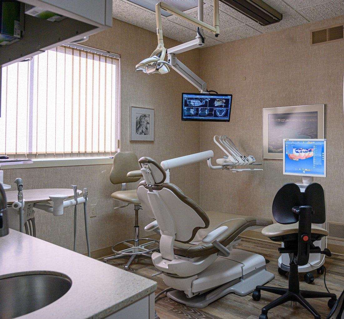 A modern dental chair featuring a monitor and computer next to dentist's chair in troy