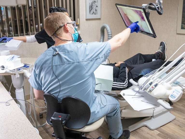 dentist showing patient their tooth on screen above dental chair